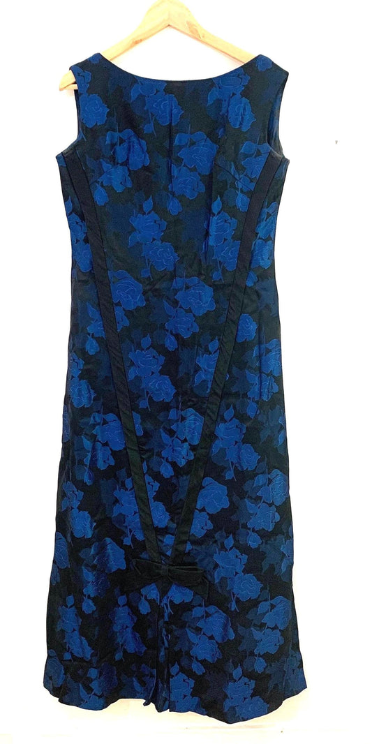 May include: A long blue and black sleeveless dress with a floral pattern. The dress has a scoop neck and a fitted bodice. The skirt is full and flowing. The dress is accented with black ribbon trim.