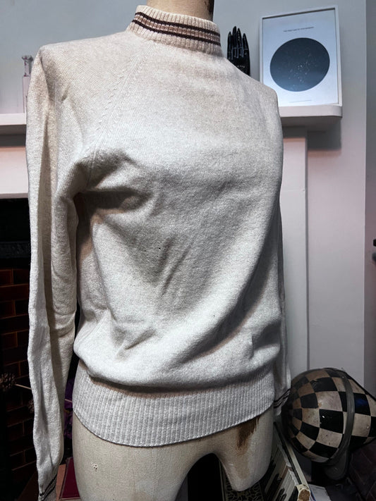 May include: A white sweater with a brown and white striped collar. The sweater has long sleeves and a ribbed hem.